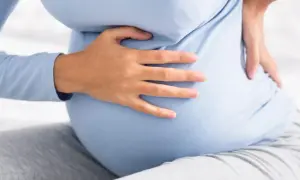 Kobieta w ciąży trzyma się za bok, odczuwając ból sugerujący kolkę nerkową w ciąży.
