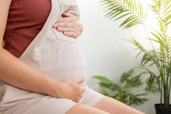 Czekając na poród, ciężarna kobieta delikatnie głaszcze swój brzuch. Szyjka macicy 2 cm, zbliża się wielkimi krokami ten wyjątkowy moment.