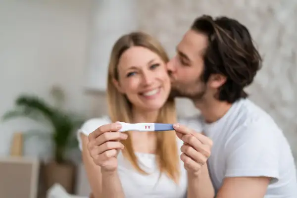 Szczęśliwa para trzyma test ciążowy z dwoma kreskami. Po trudnych doświadczeniach, to nowy początek i nadzieja na ciążę po poronieniu.
