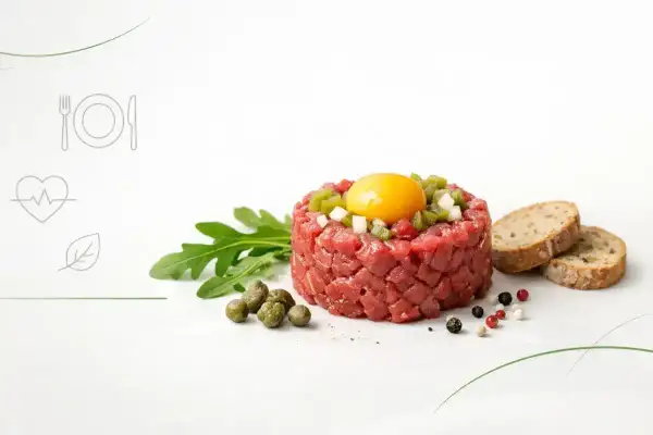 Wykwintny tatar w ciąży, z żółtkiem i dodatkami, podany z rukolą i pieczywem.