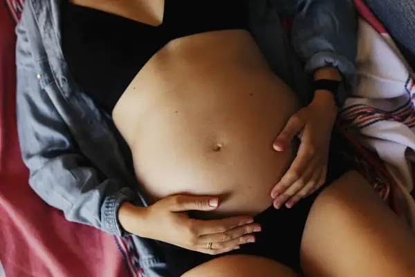 Ciężarna kobieta obejmuje brzuch. Może odczuwać ból pachwin w ciąży, ale skupia się na swoim maleństwie.