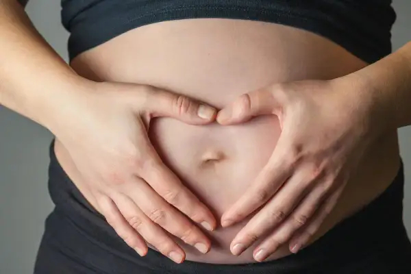Dłonie tworzą serce na brzuchu, symbolizując miłość i troskę o to, jak dziecko oddycha w brzuchu.