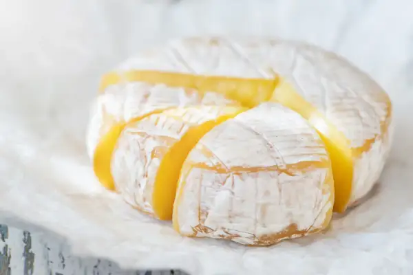 Ser camembert w ciąży, z widocznymi kawałkami, prezentuje swoje kremowe wnętrze.
