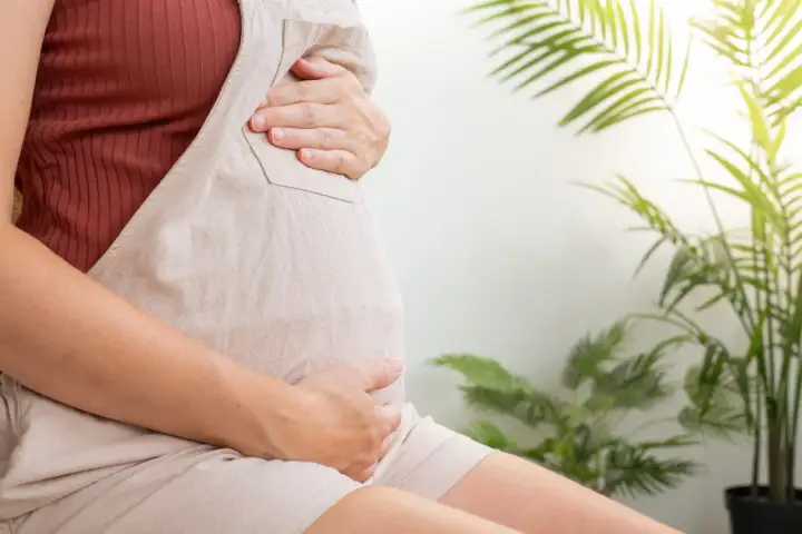 Czekając na poród, ciężarna kobieta delikatnie głaszcze swój brzuch. Szyjka macicy 2 cm, zbliża się wielkimi krokami ten wyjątkowy moment.
